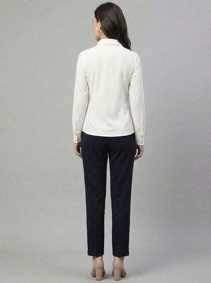 Woman wearing a white shirt and black pants on a gray background